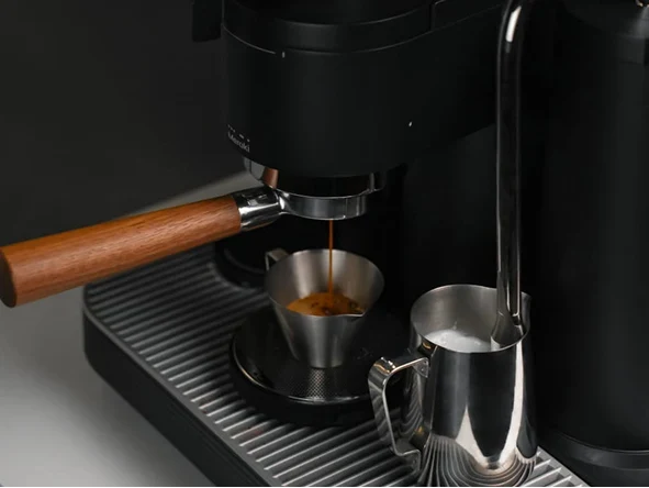 Espresso fließt aus dem Siebträger der Meraki Espressomaschine in einen Metallbecher.
