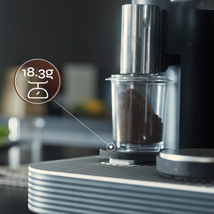 Gemahlener Kaffee im transparenten Dosierbehälter auf der Meraki Mahlwaage mit eingeblendeter Gewichtsangabe von 18.3 g.